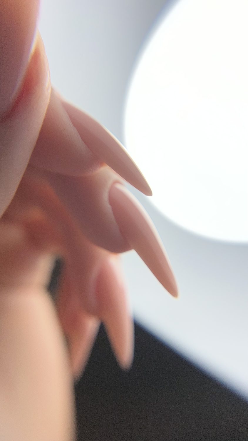 Long nude stiletto nails in soft light